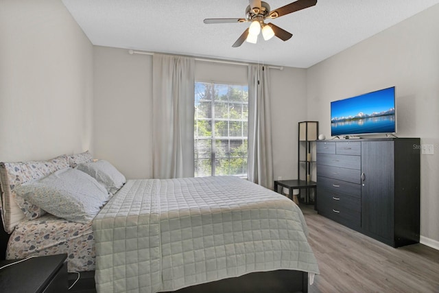 bedroom with a textured ceiling, ceiling fan, and hardwood / wood-style flooring