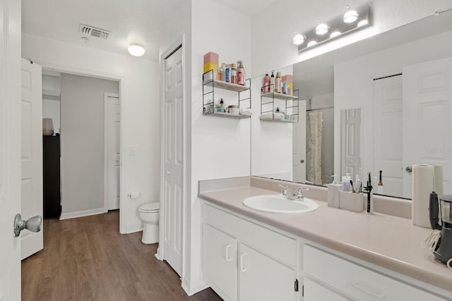 bathroom featuring wood-type flooring, vanity, and toilet