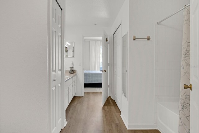 bathroom with hardwood / wood-style flooring, tiled shower / bath, and vanity