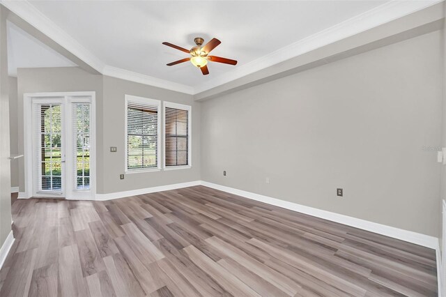 empty room with crown molding, a ceiling fan, light wood-style flooring, and baseboards