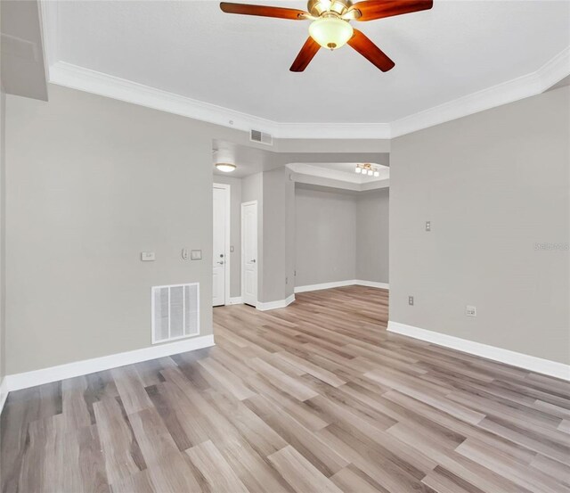 spare room featuring light wood-style floors, visible vents, and crown molding