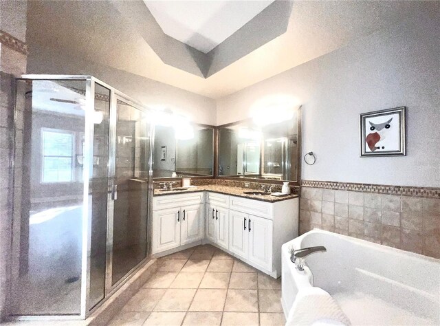 bathroom with double vanity, a stall shower, a bath, tile patterned flooring, and a sink