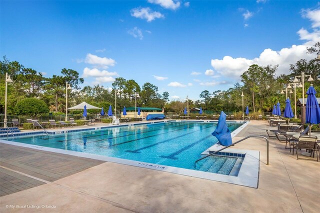 community pool with a patio and fence