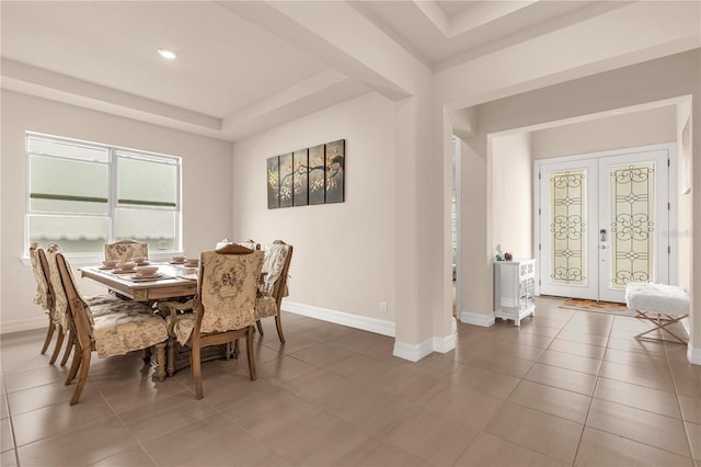 dining area with french doors, a tray ceiling, and dark tile patterned flooring