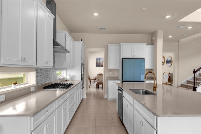 kitchen with appliances with stainless steel finishes, white cabinetry, an island with sink, sink, and light tile patterned floors