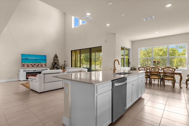 kitchen with white cabinetry, an island with sink, dishwasher, sink, and a healthy amount of sunlight