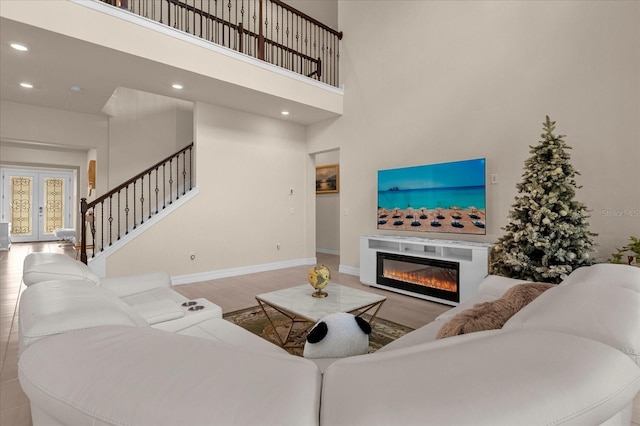 living room with a towering ceiling, light hardwood / wood-style floors, and french doors