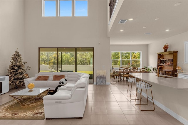 living room with sink, light tile patterned floors, and a towering ceiling