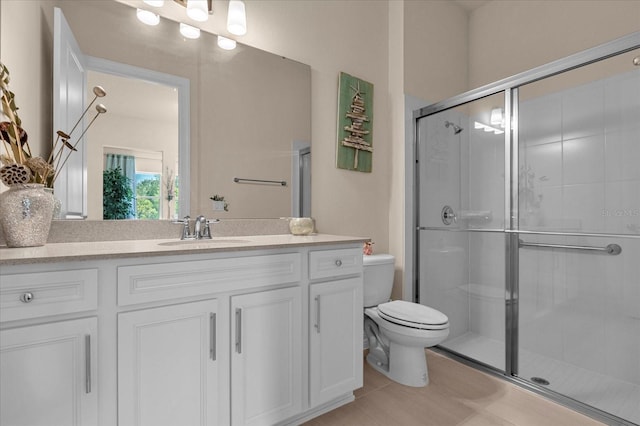 bathroom featuring tile patterned floors, vanity, toilet, and a shower with shower door