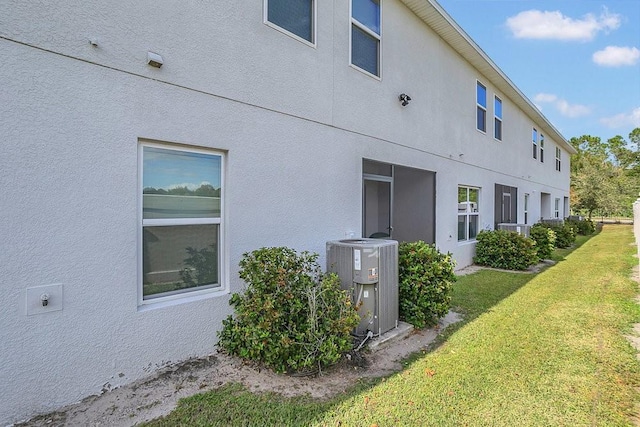 view of home's exterior with cooling unit and a yard