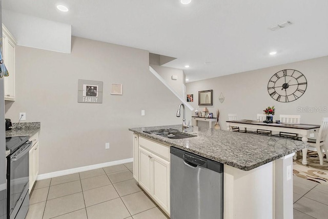 kitchen with sink, white cabinetry, stone countertops, a center island with sink, and stainless steel appliances