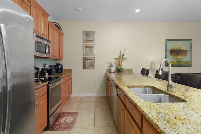 kitchen featuring light stone counters, sink, light tile floors, and appliances with stainless steel finishes