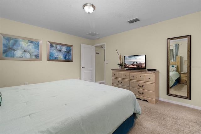 bedroom with light colored carpet and a textured ceiling