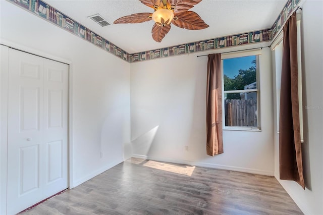 empty room featuring ceiling fan, a textured ceiling, and light wood-type flooring