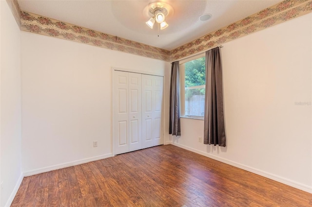 unfurnished bedroom with a closet, dark wood-type flooring, and ceiling fan