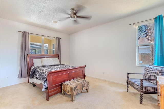 bedroom with ceiling fan, light colored carpet, and a textured ceiling