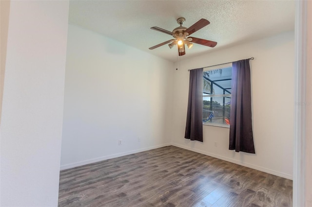 empty room with ceiling fan, dark wood-type flooring, and a textured ceiling