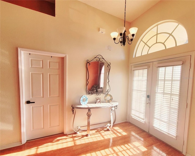 doorway to outside with lofted ceiling, an inviting chandelier, wood-type flooring, and french doors