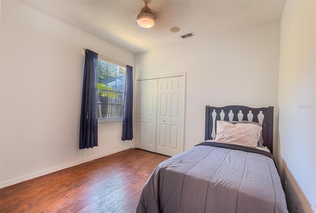 bedroom with dark hardwood / wood-style floors, ceiling fan, a textured ceiling, and a closet