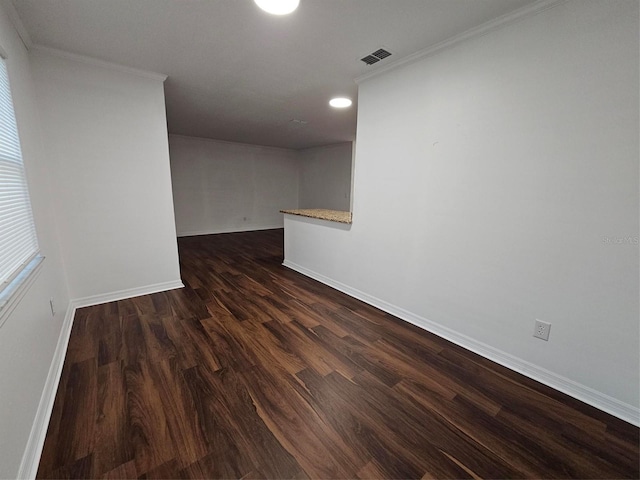 empty room with dark hardwood / wood-style flooring and ornamental molding