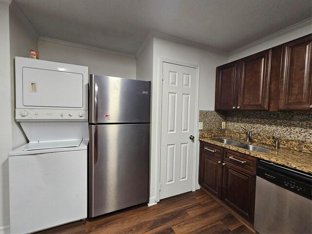 kitchen with appliances with stainless steel finishes, ornamental molding, sink, stacked washer and clothes dryer, and dark hardwood / wood-style floors