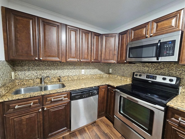 kitchen featuring light stone counters, stainless steel appliances, crown molding, sink, and wood-type flooring