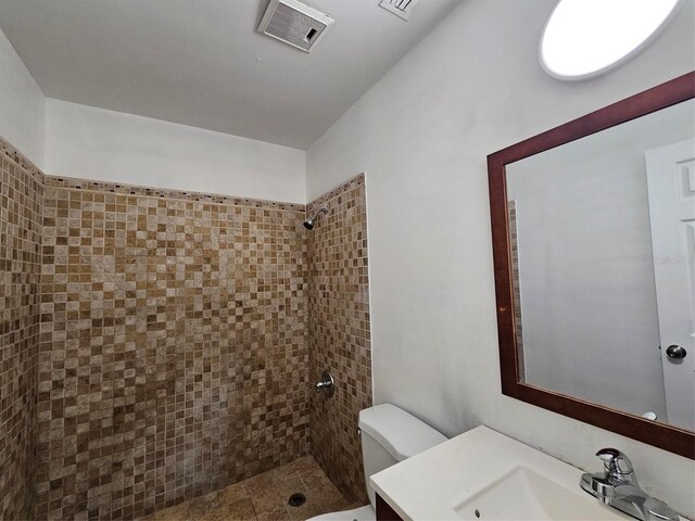 bathroom featuring tiled shower, vanity, and toilet