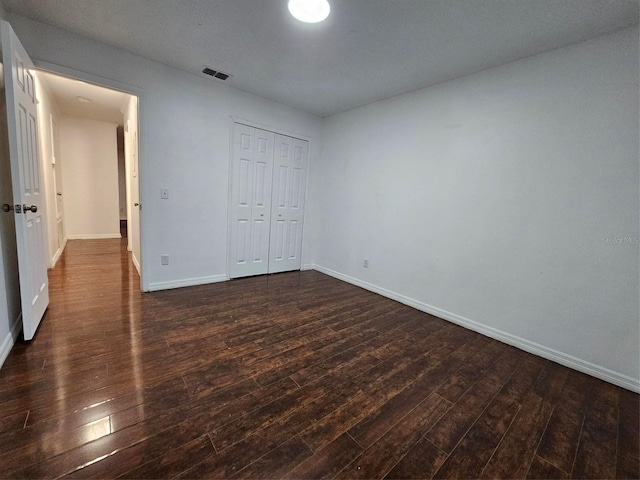 unfurnished bedroom featuring a closet and dark wood-type flooring