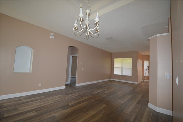 empty room featuring an inviting chandelier, a textured ceiling, and dark hardwood / wood-style floors