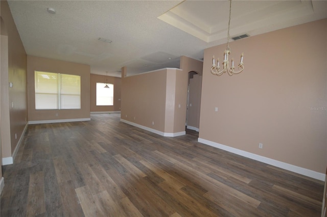 spare room featuring a notable chandelier, a textured ceiling, and dark hardwood / wood-style floors