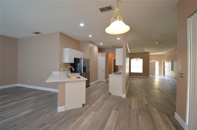 kitchen featuring dark hardwood / wood-style floors, sink, white cabinets, kitchen peninsula, and hanging light fixtures