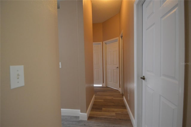 corridor with a textured ceiling and dark hardwood / wood-style floors