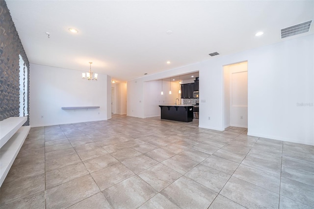 unfurnished living room featuring sink, a notable chandelier, and light tile floors