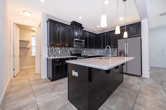 kitchen featuring appliances with stainless steel finishes, tasteful backsplash, a kitchen island with sink, sink, and pendant lighting