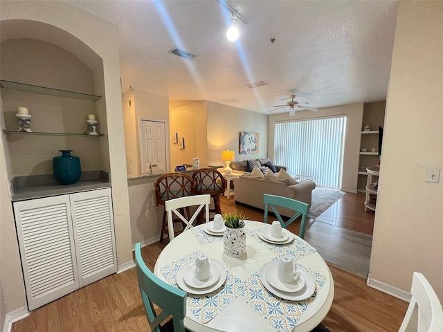 dining room with built in shelves, a textured ceiling, and hardwood / wood-style flooring