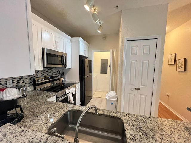 kitchen featuring light hardwood / wood-style floors, rail lighting, sink, white cabinetry, and appliances with stainless steel finishes