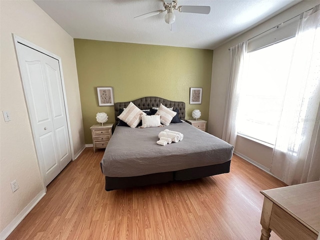 bedroom featuring ceiling fan, multiple windows, light hardwood / wood-style floors, and a closet