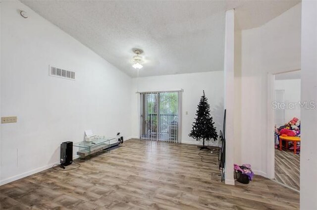 interior space featuring hardwood / wood-style floors, ceiling fan, high vaulted ceiling, and a textured ceiling