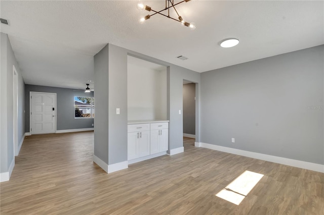 interior space featuring ceiling fan with notable chandelier and light hardwood / wood-style floors