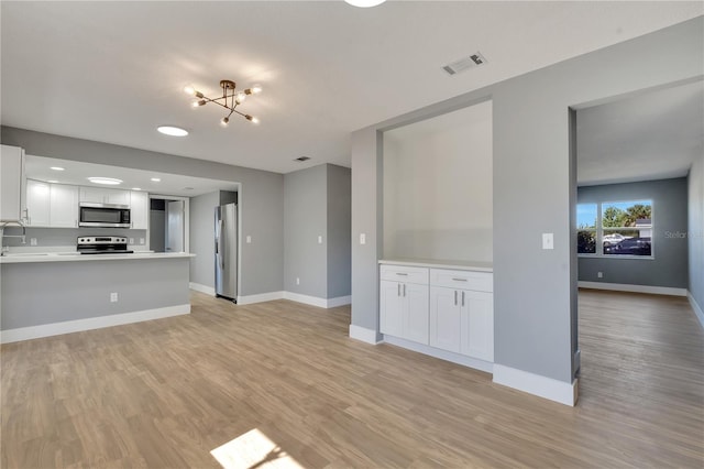 unfurnished living room with sink, a chandelier, and light wood-type flooring