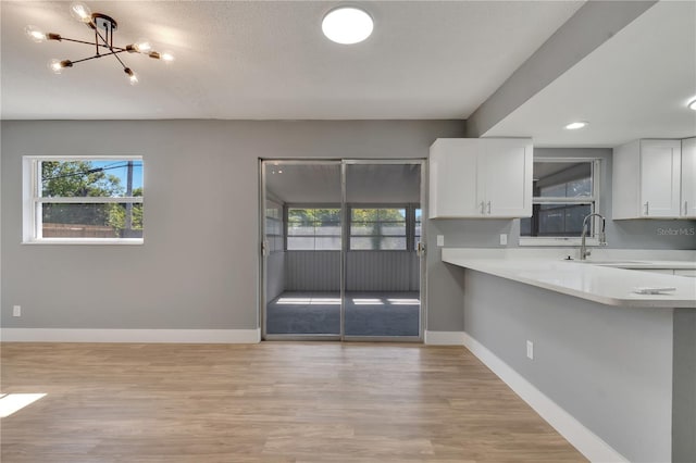 kitchen featuring a healthy amount of sunlight, light hardwood / wood-style flooring, sink, and white cabinetry