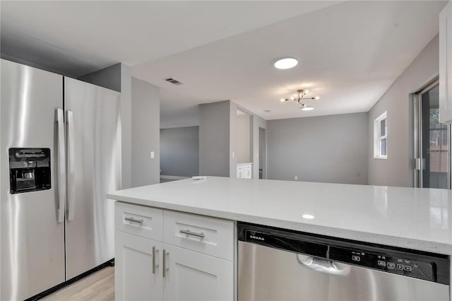 kitchen featuring white cabinets, light hardwood / wood-style flooring, stainless steel appliances, and light stone countertops