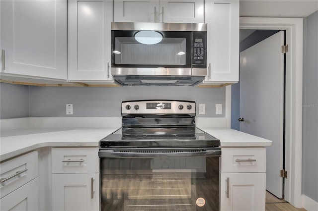 kitchen with electric stove, white cabinets, and light stone counters