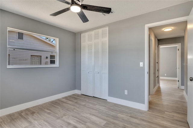 unfurnished bedroom with a closet, light hardwood / wood-style flooring, ceiling fan, and a textured ceiling