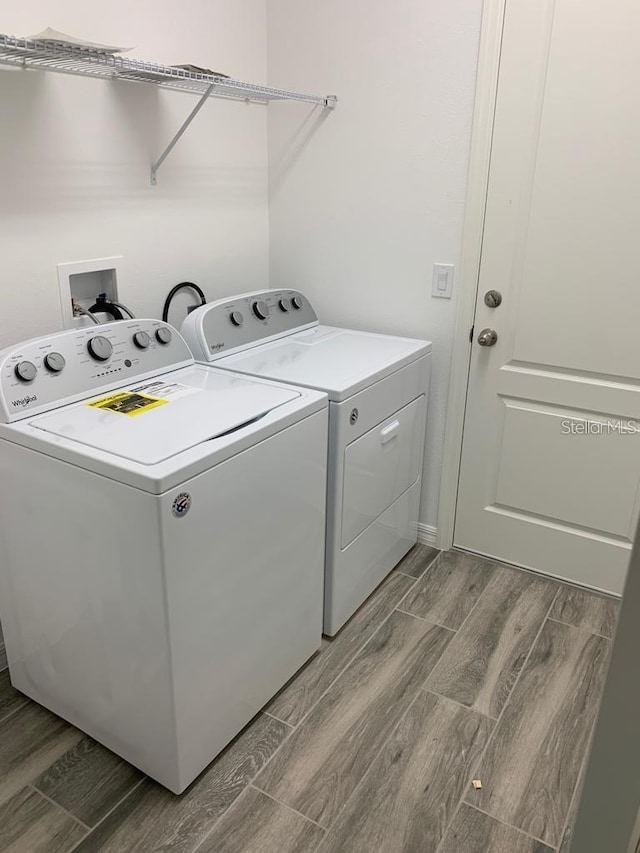 clothes washing area featuring wood-type flooring, hookup for a washing machine, and separate washer and dryer