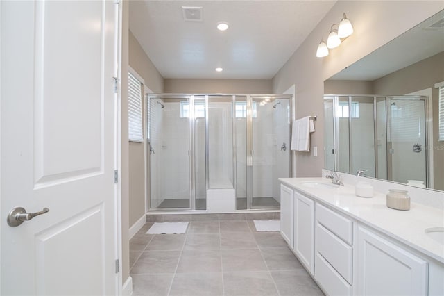 bathroom with a shower with door, dual bowl vanity, and tile floors