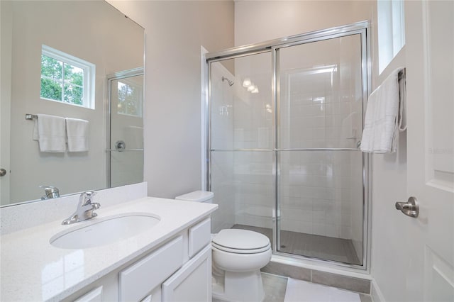 bathroom with tile floors, vanity with extensive cabinet space, an enclosed shower, and toilet