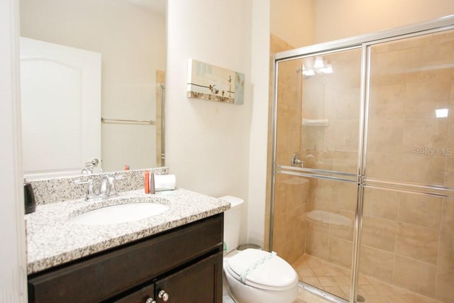 bathroom with toilet, a shower with shower door, and vanity