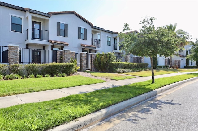 view of front of home featuring a balcony and a front yard