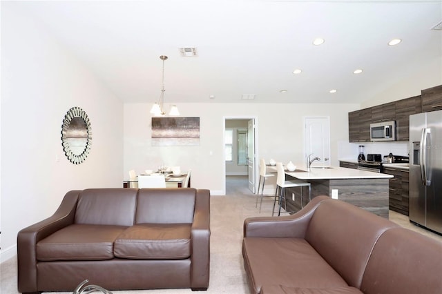 living room featuring light colored carpet, sink, and a notable chandelier